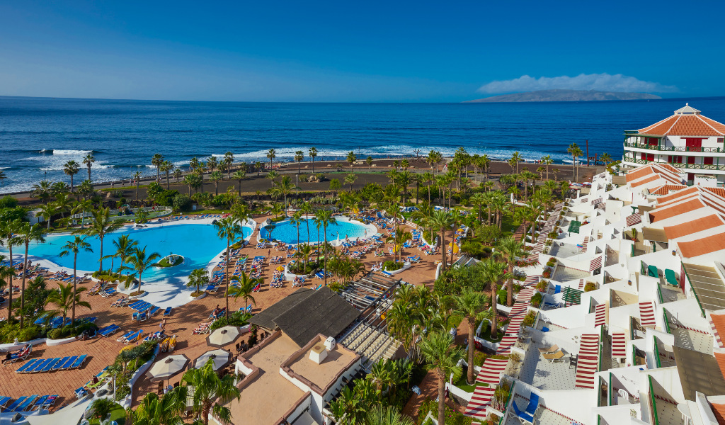 Complejo hotelero en Tenerife con piscinas frente al mar y áreas de descanso.