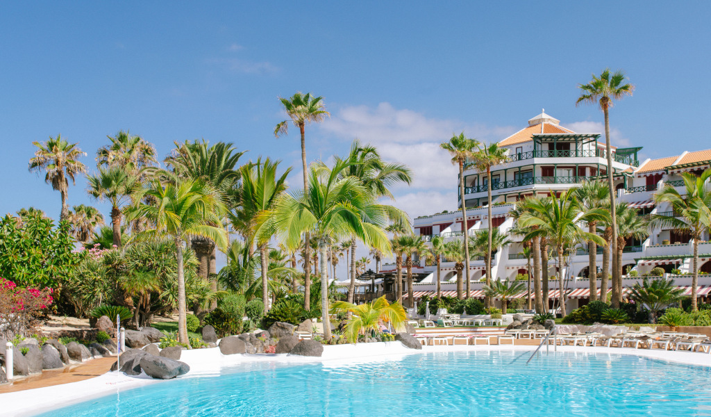 Piscina y palmeras frente a un hotel en Tenerife.