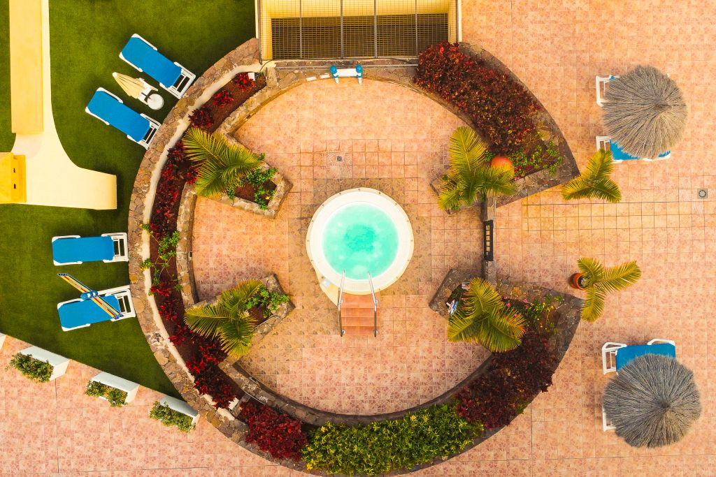 Vista aérea de una piscina circular rodeada de tumbonas y palmeras en Tenerife.