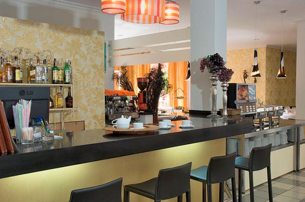 Barra de un bar con botellas y sillas altas en un restaurante de Tenerife.