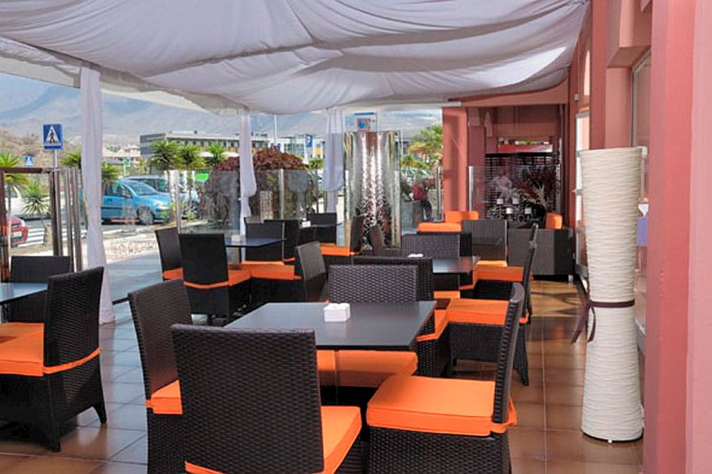 Terraza de restaurante con mesas y sillas en Santa Cruz de Tenerife.