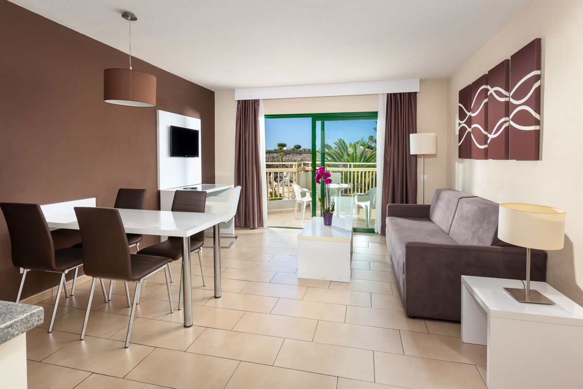 Sala de estar con muebles modernos y balcón con vista de palmeras en Tenerife.
