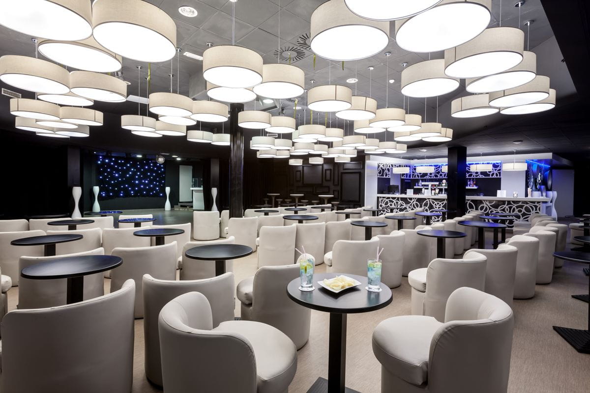Bar moderno con mesas y sillas blancas en un hotel en Tenerife.