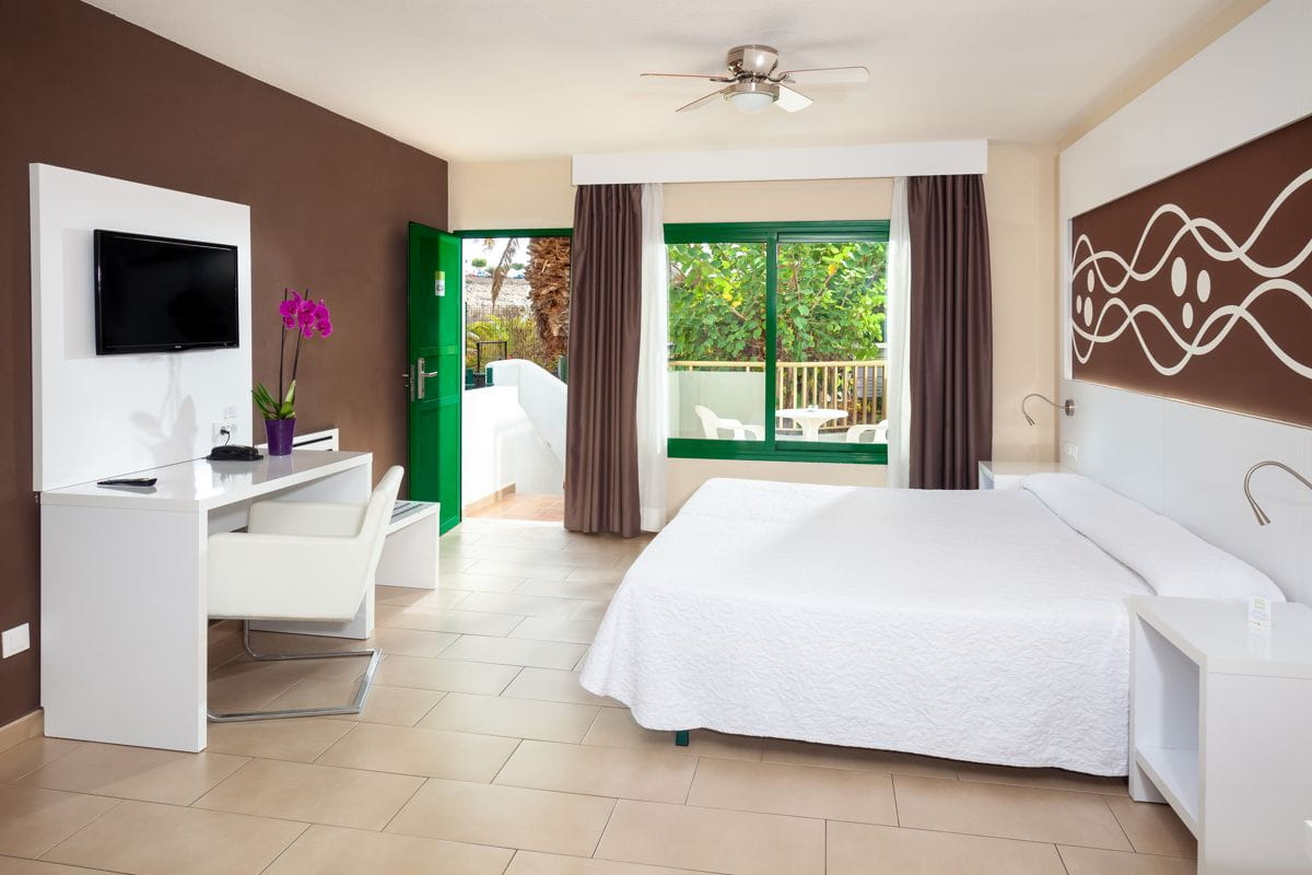 Habitación de hotel con cama doble, escritorio y vista al jardín en Tenerife.