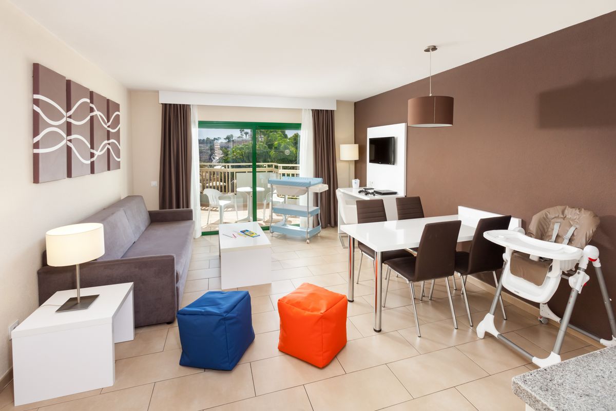 Sala de estar con sofá, mesa de comedor y sillas en un apartamento de Tenerife.