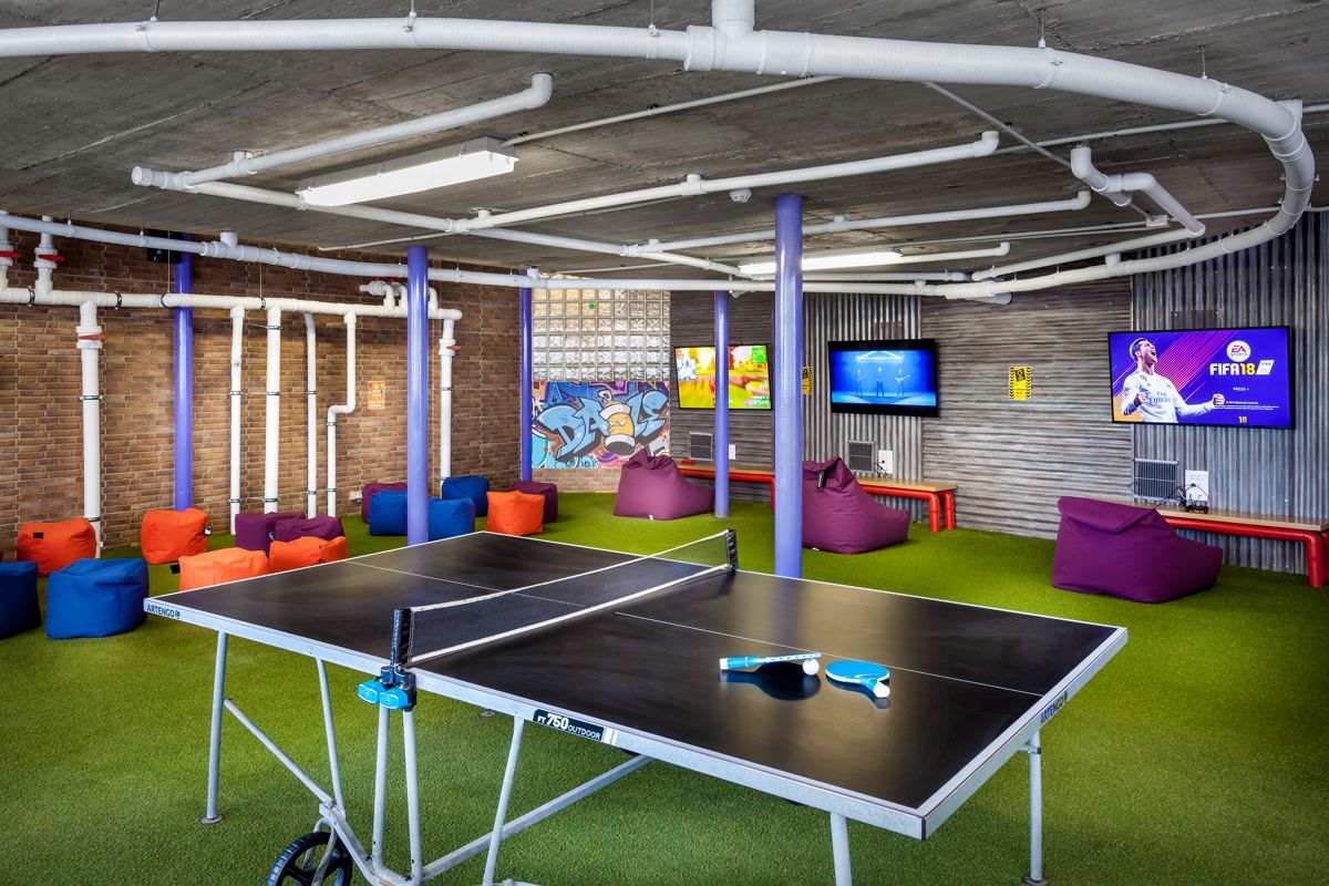 Sala de juegos con mesa de ping-pong y pufs coloridos en Tenerife.