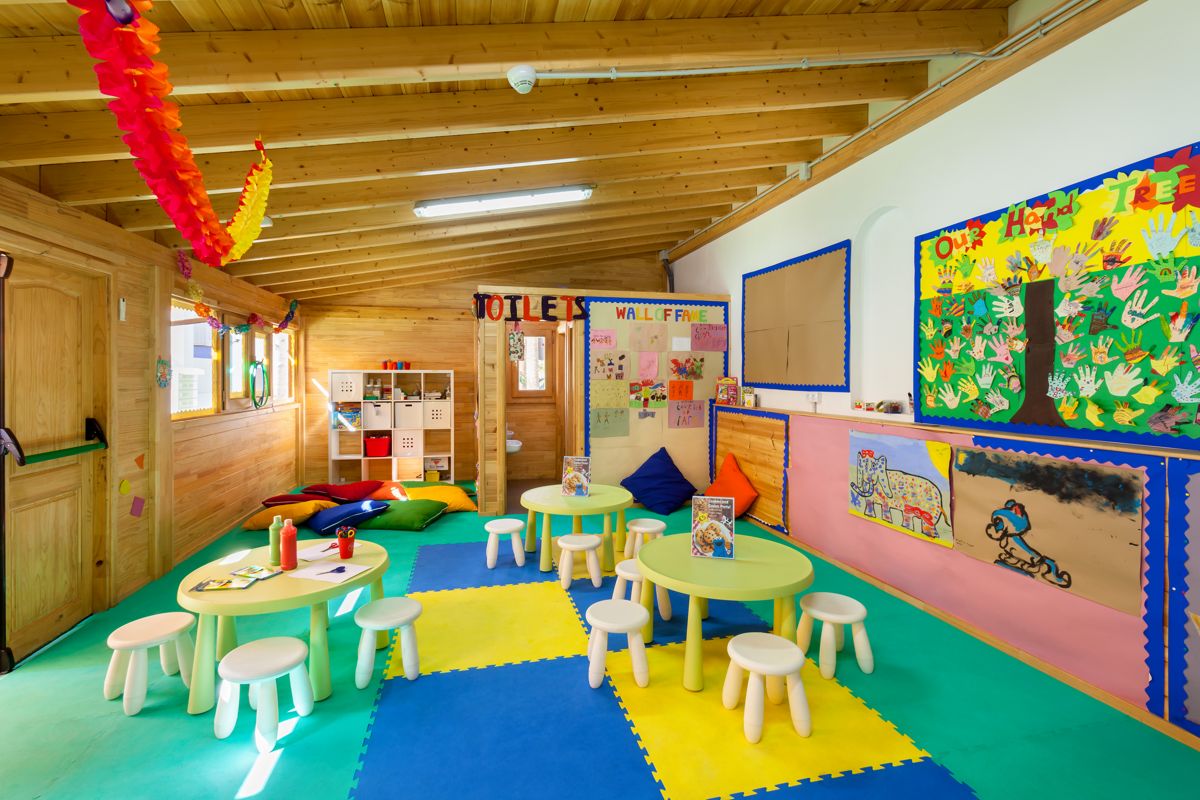 Aula colorida infantil en Tenerife con mesas, sillas y decoraciones.