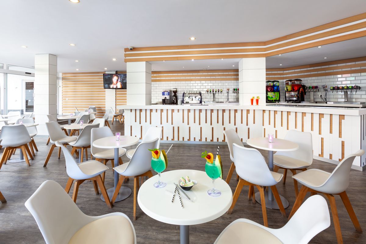 Bar moderno con sillas blancas y mesas redondas en Santa Cruz de Tenerife.