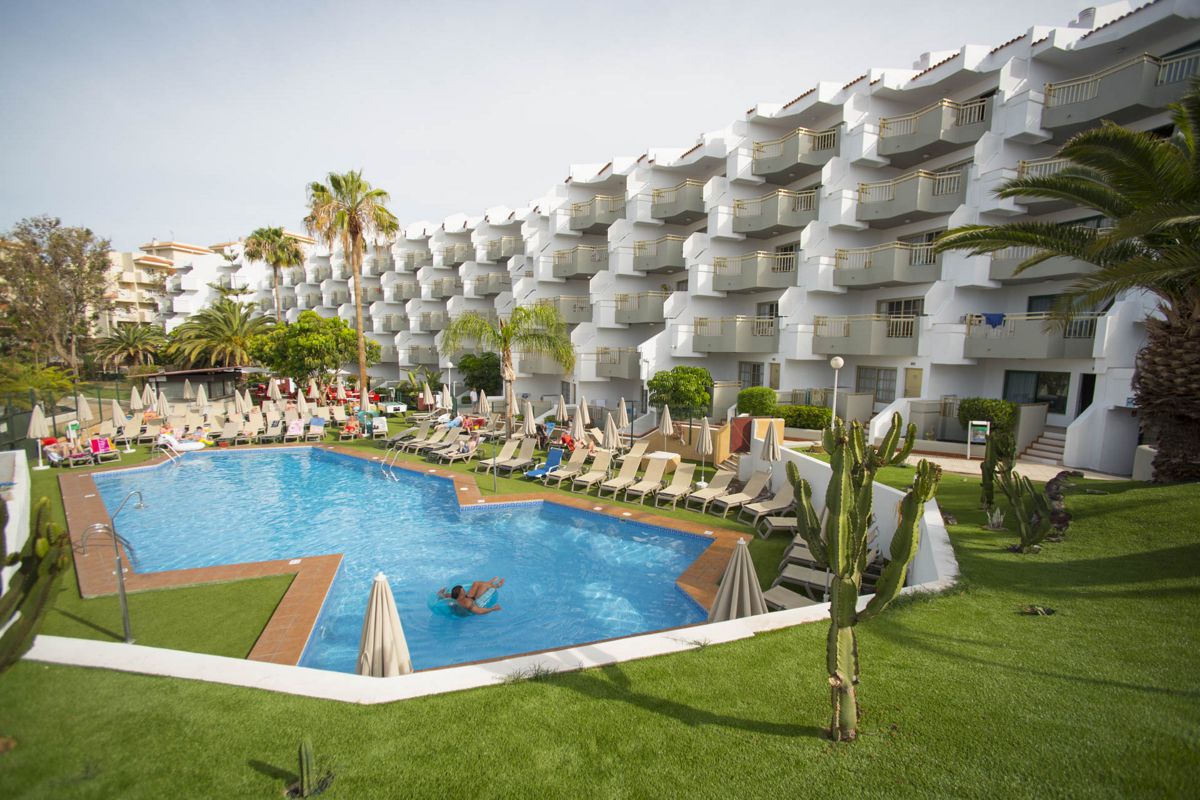 Piscina y tumbonas frente a un edificio en Santa Cruz de Tenerife.