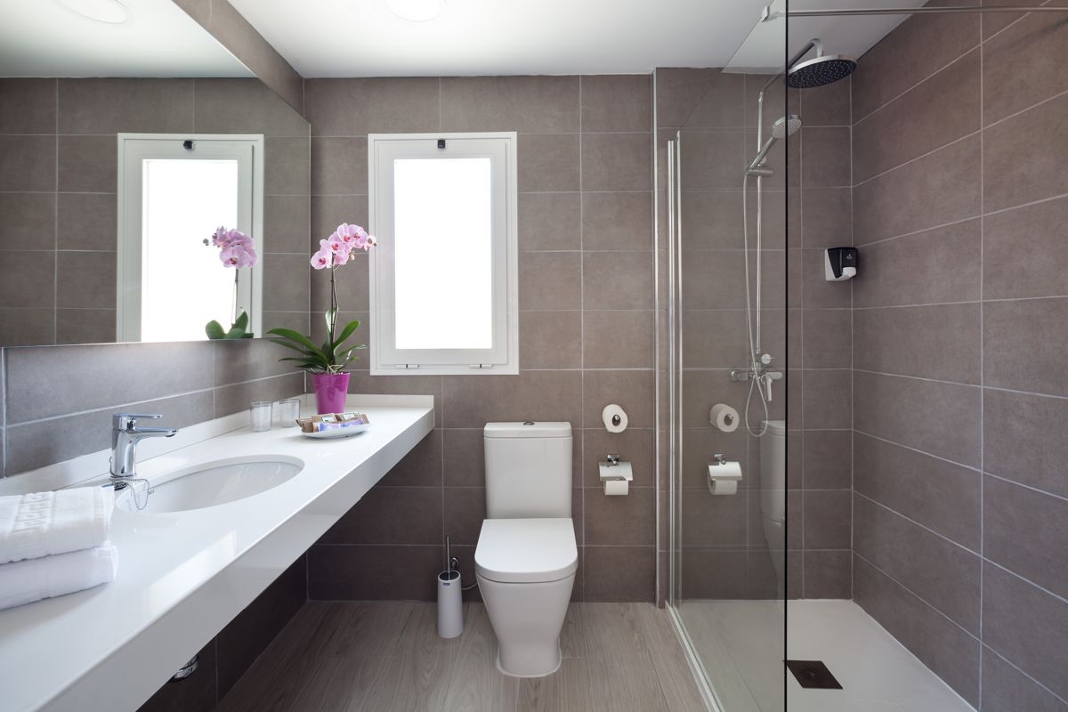 Baño moderno con ducha, lavabo, inodoro y ventana en apartamento de Tenerife.