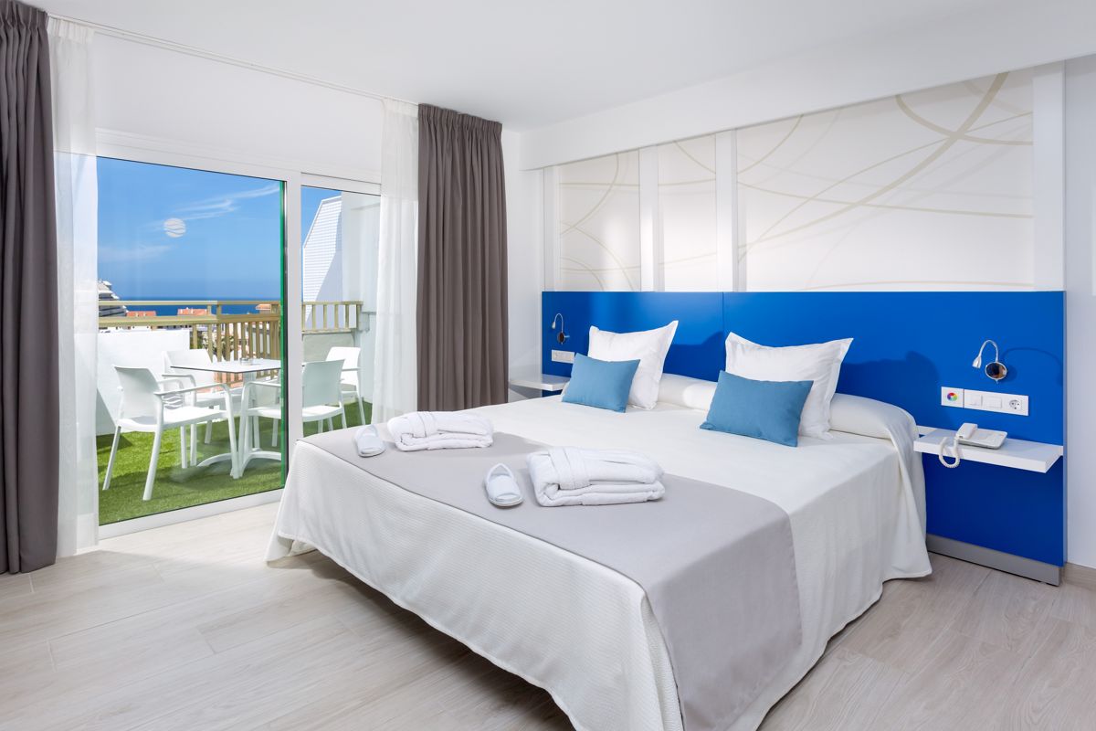 Habitación de hotel en Tenerife con cama doble, terraza y vista al océano.