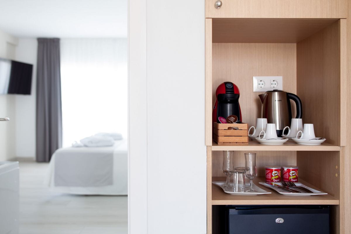 Estante con cafetera, tazas y hervidor en habitación de hotel en Tenerife.