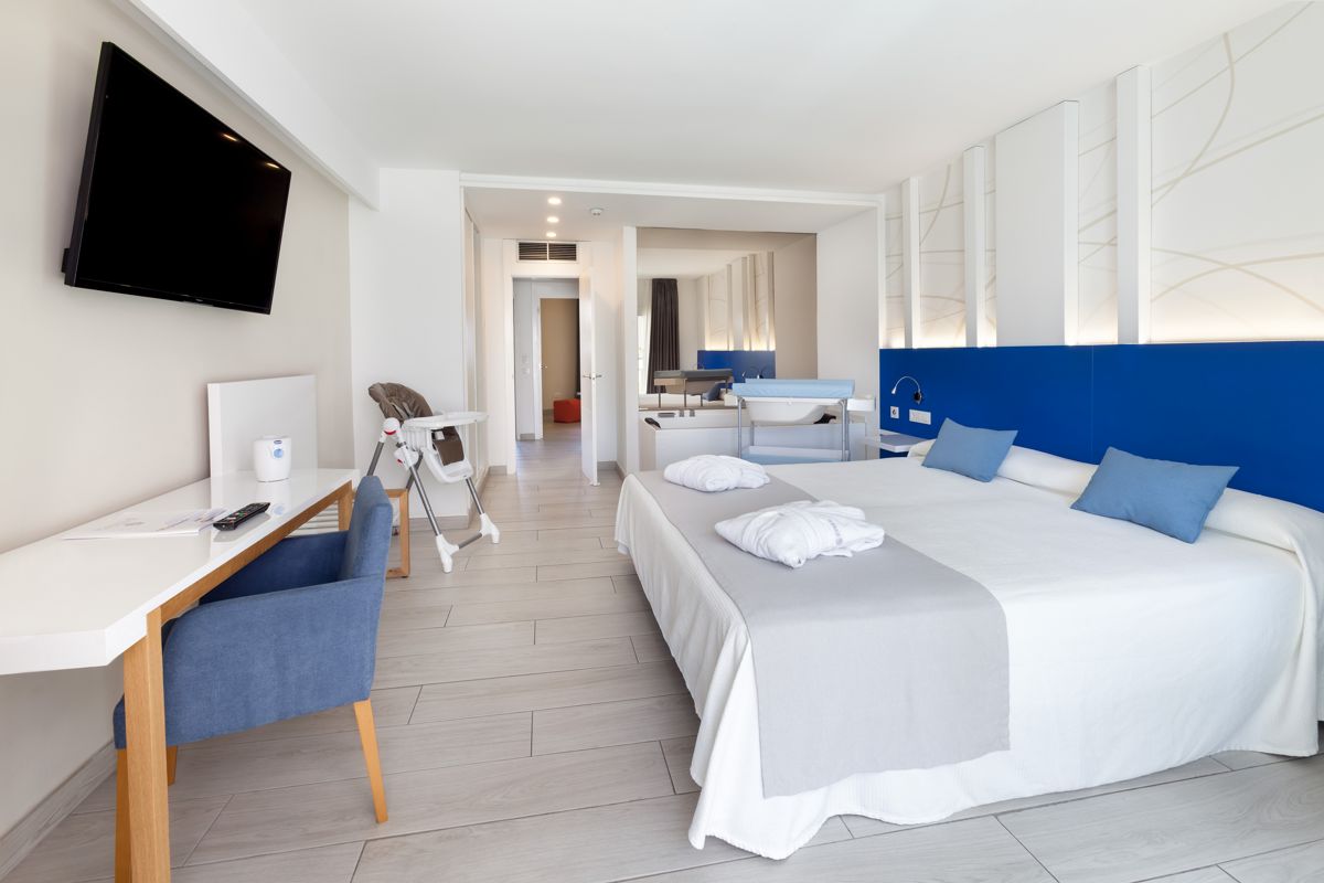 Habitación de hotel en Tenerife con cama doble, escritorio, y televisor en la pared.