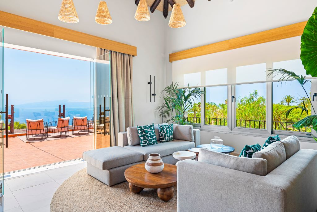 Sala de estar con sofá y vistas al océano en Tenerife desde terraza abierta.