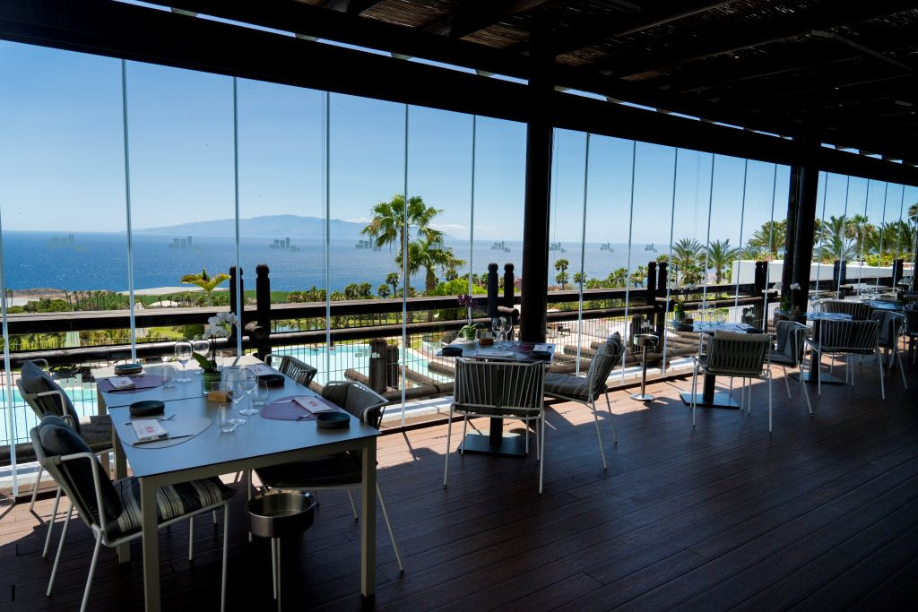 Restaurante con vista al mar y a La Gomera desde Tenerife, mesas preparadas para comer.