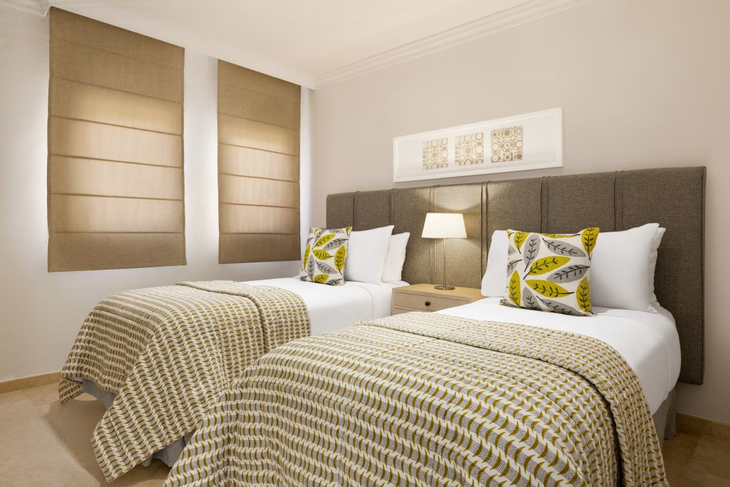 Dos camas individuales con colchas estampadas y cojines en habitación de hotel en Tenerife.