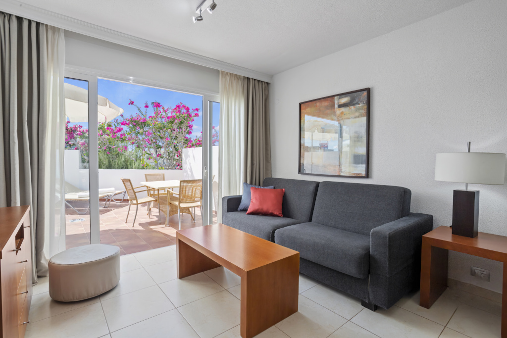 Sala de estar con sofá gris y vista a terraza con flores en Tenerife.