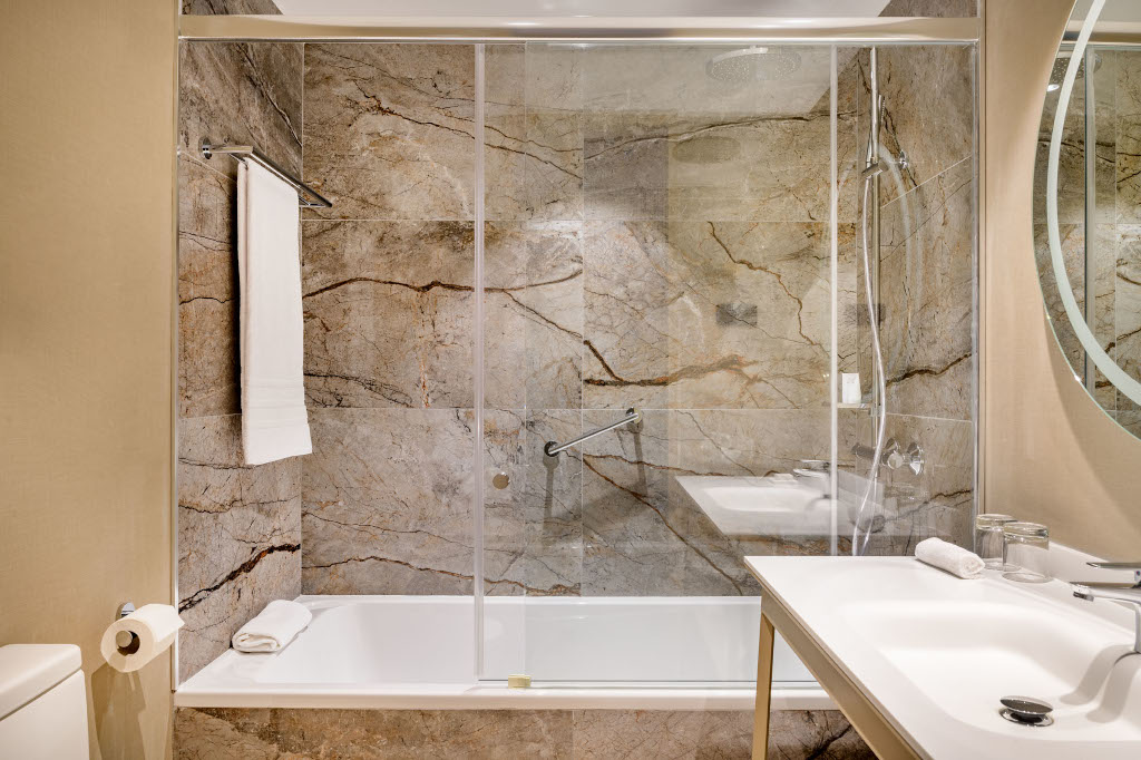 Baño con ducha de mármol y espejo grande en un hotel de Tenerife.