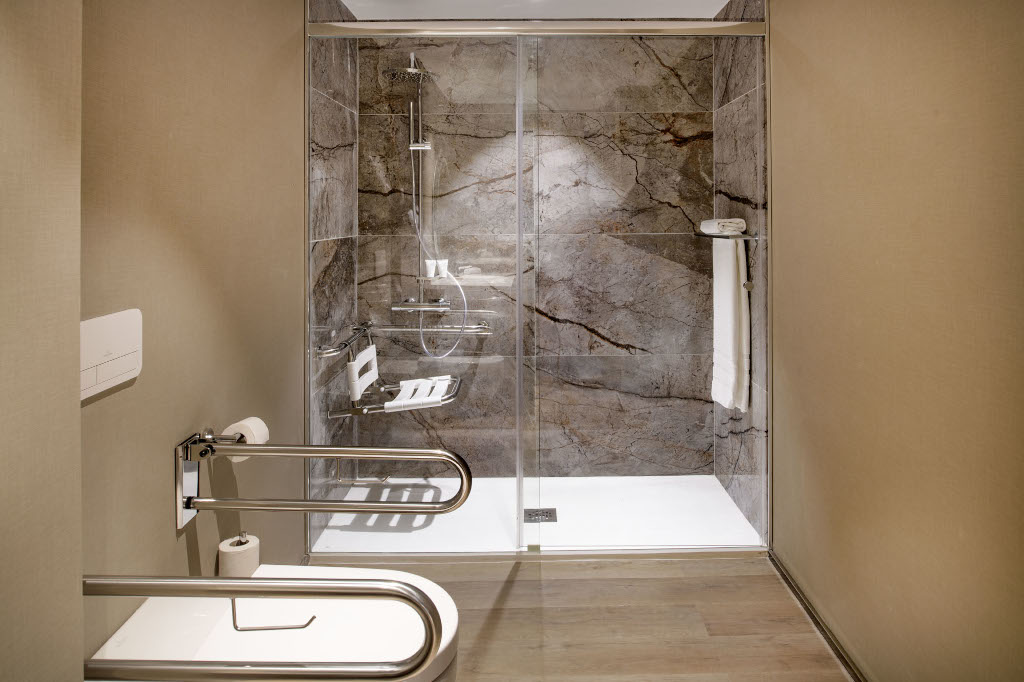 Ducha accesible con pasamanos y banco en baño de hotel en Tenerife.