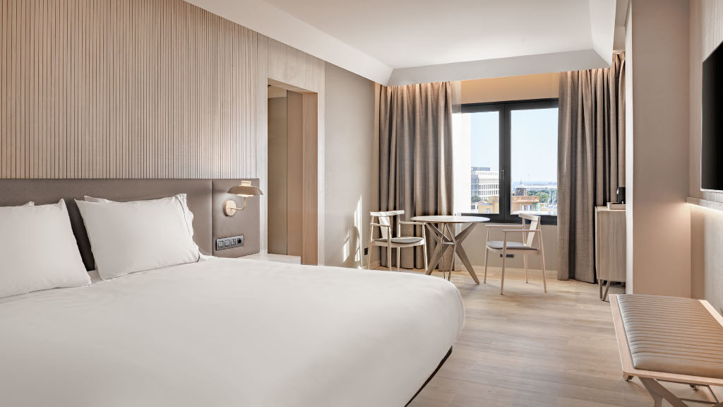Habitación de hotel en Tenerife con cama doble, mesa y sillas junto a la ventana.