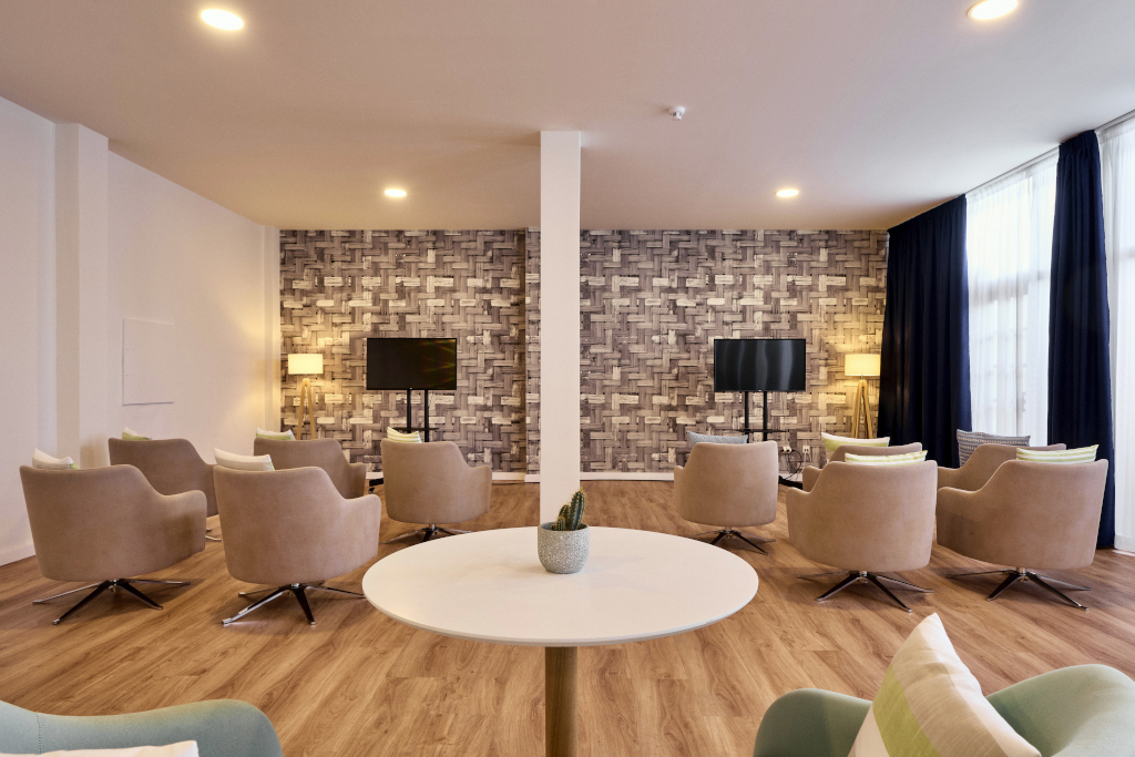 Sala de reuniones en Tenerife con sillas beige y dos pantallas de televisión.