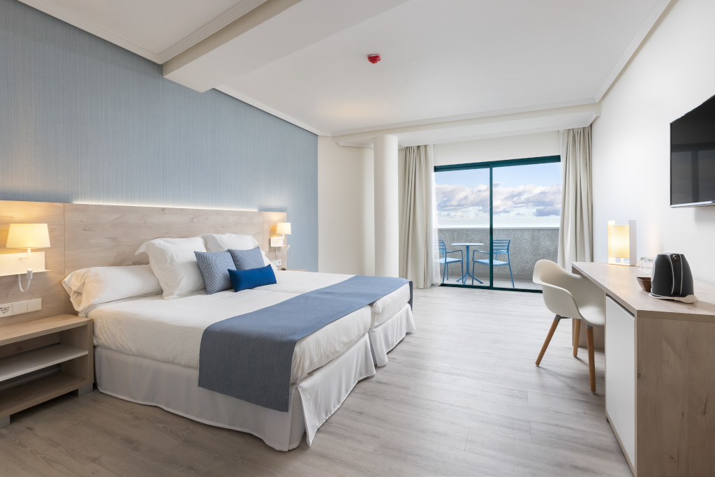 Habitación moderna con cama doble y balcón con vista al mar en Tenerife.