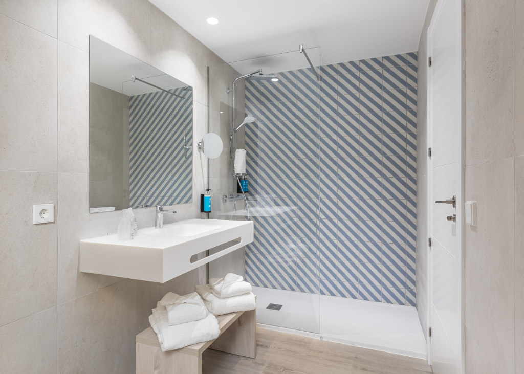 Baño moderno con azulejos de rayas azules en hotel de Tenerife.