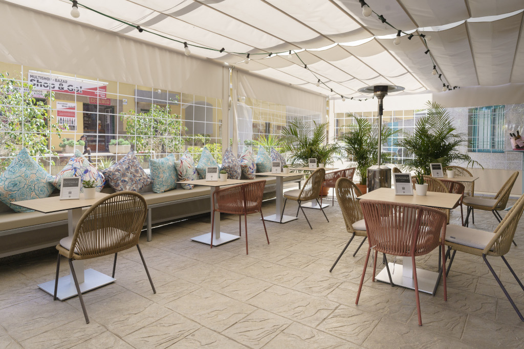 Terraza de cafetería en Tenerife con mesas, sillas y cojines coloridos.