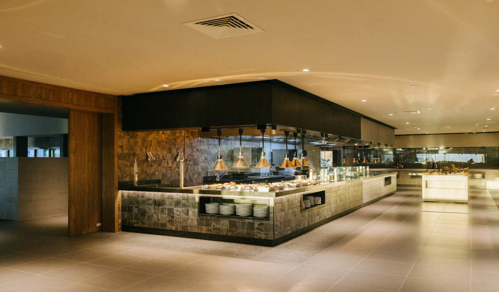 Área de buffet moderno en hotel de Tenerife, con platos y lámparas colgantes.