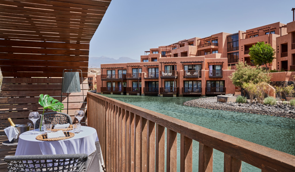 Terraza con mesa y sillas junto a un canal de agua en un complejo turístico en Tenerife.