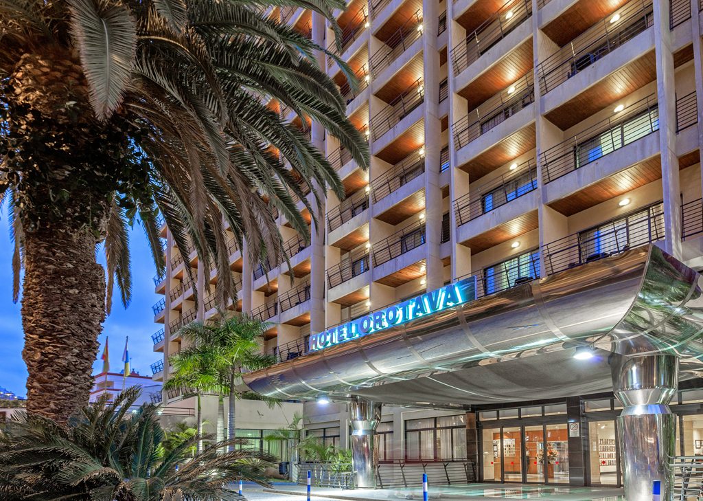 Entrada iluminada del Hotel Orotava en Tenerife, rodeada de palmeras.
