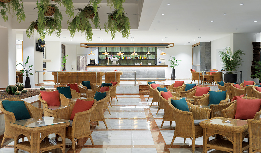 Sala de estar con sillas de mimbre y barra en hotel de Tenerife.