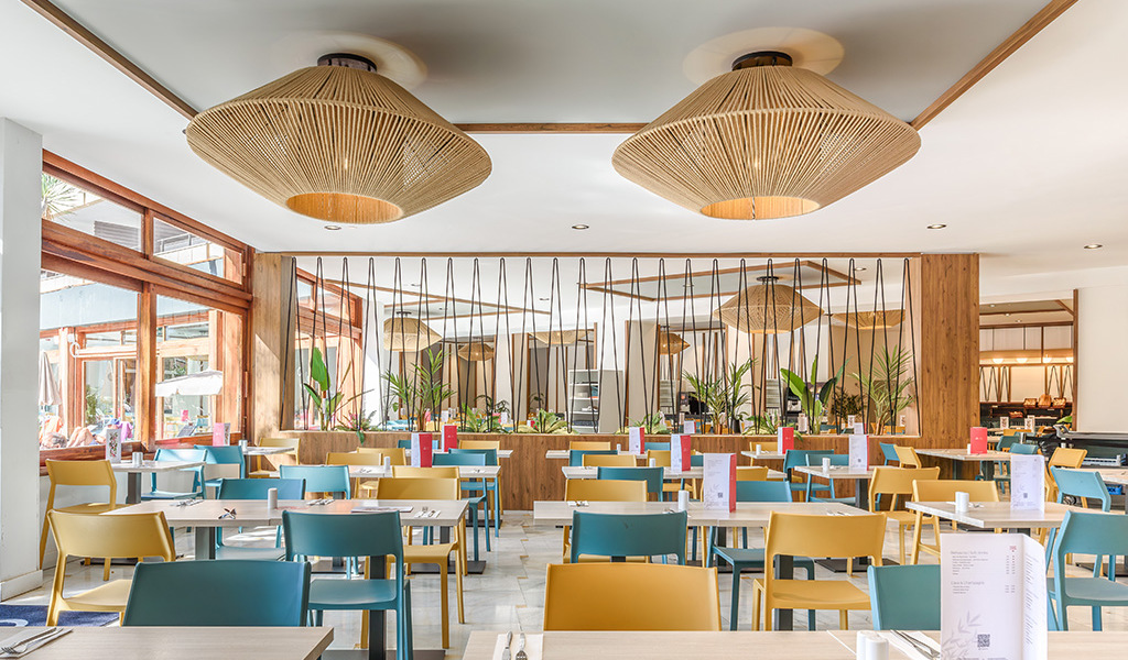 Restaurante moderno con sillas de colores y lámparas de mimbre en Tenerife.