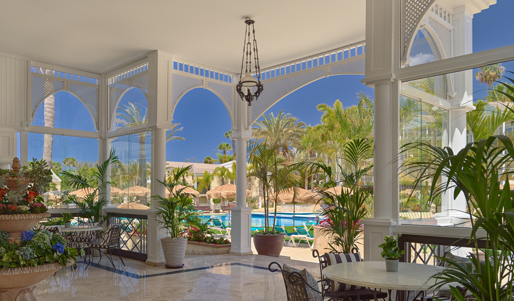 Vista desde un patio interior hacia una piscina rodeada de palmeras en Tenerife.