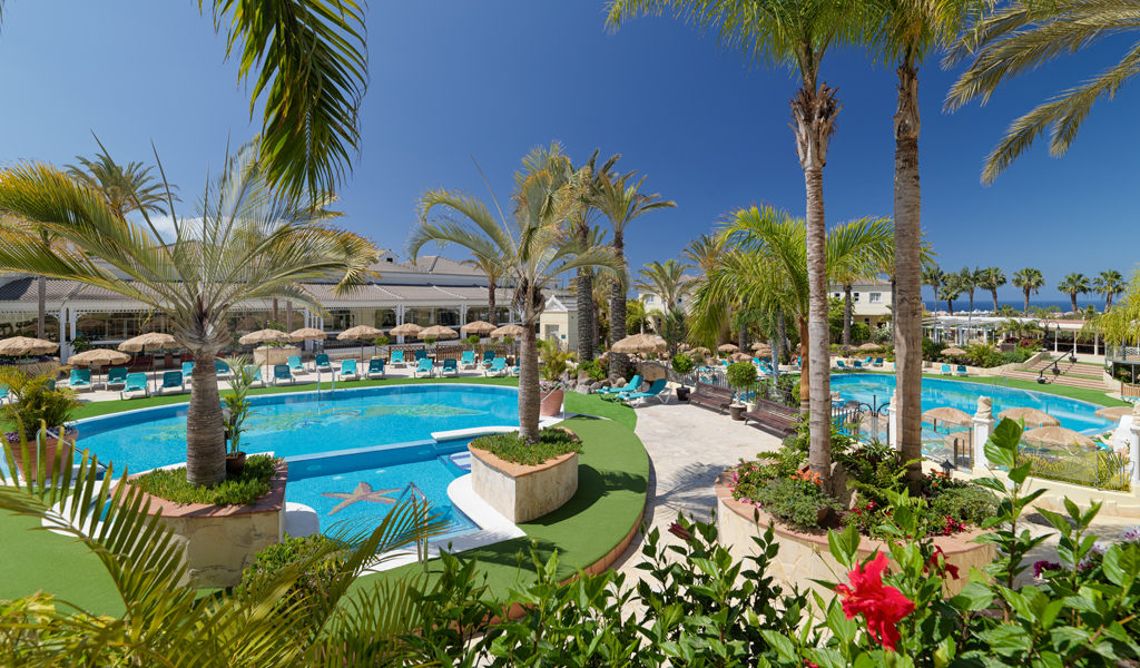 Piscina rodeada de palmeras en un hotel de Costa Adeje, Tenerife.