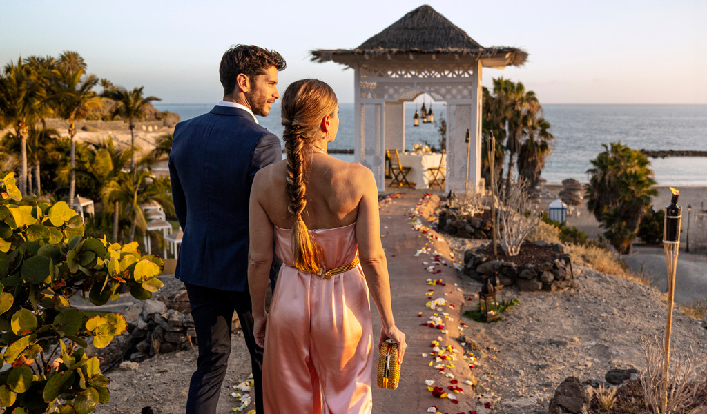 Pareja caminando hacia una estructura decorada junto al mar en Tenerife.