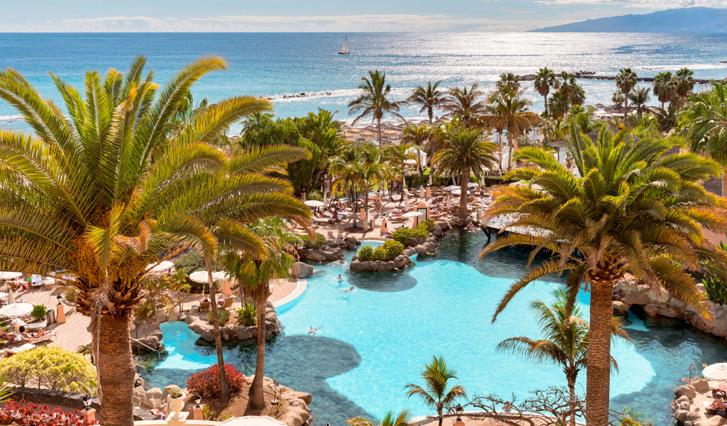 Piscina rodeada de palmeras y vistas al mar en Tenerife.