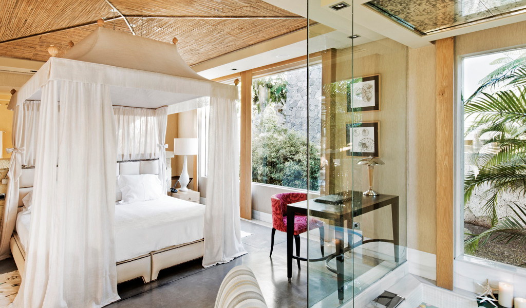 Habitación con cama con dosel, escritorio y ventana con vista a jardín en Tenerife.