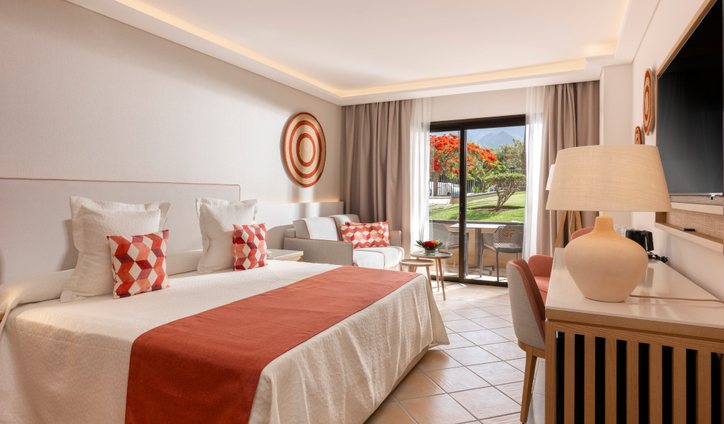 Habitación de hotel en Tenerife con cama, balcón y vista al jardín.
