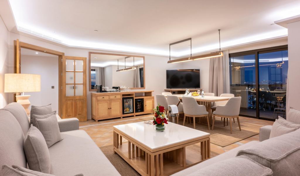 Sala de estar elegante con sofá, mesa de centro, mesa de comedor y televisión en apartamento de Tenerife.