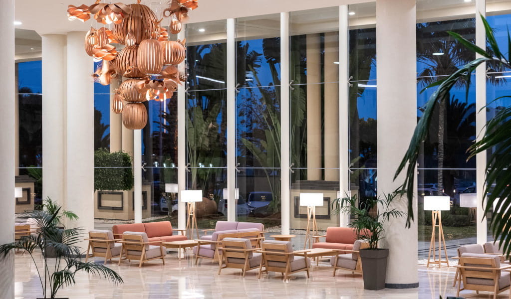 Sala de estar con sillones, lámparas y gran lámpara colgante en hotel de Tenerife.