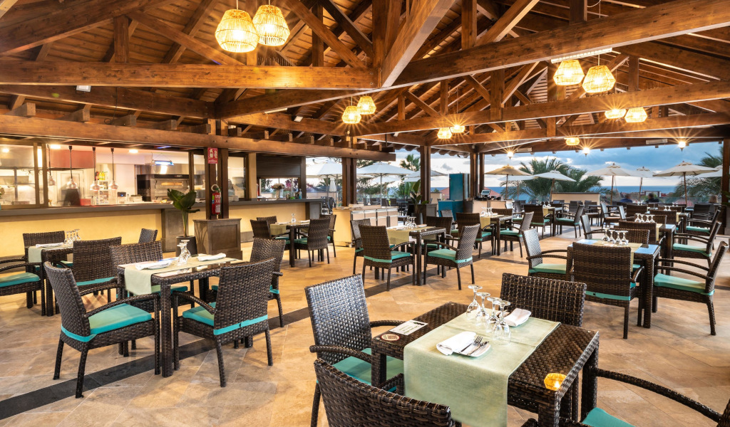 Restaurante al aire libre con mesas preparadas en Tenerife, con vistas al paisaje al atardecer.