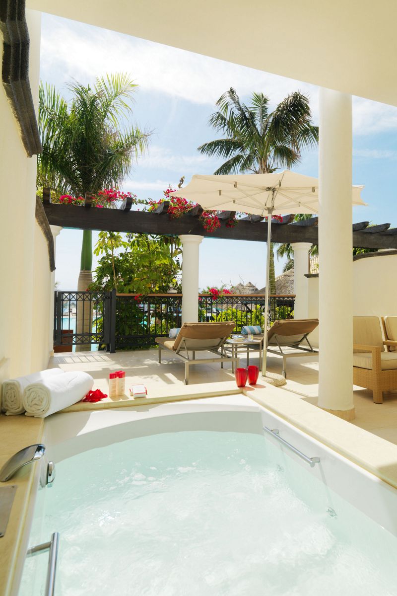 Terraza con jacuzzi, tumbonas y sombrilla en un hotel de Tenerife.