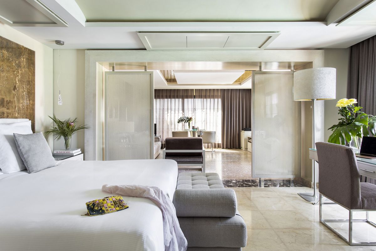 Habitación de hotel en Tenerife con cama, escritorio, sofá y cortinas cerradas.