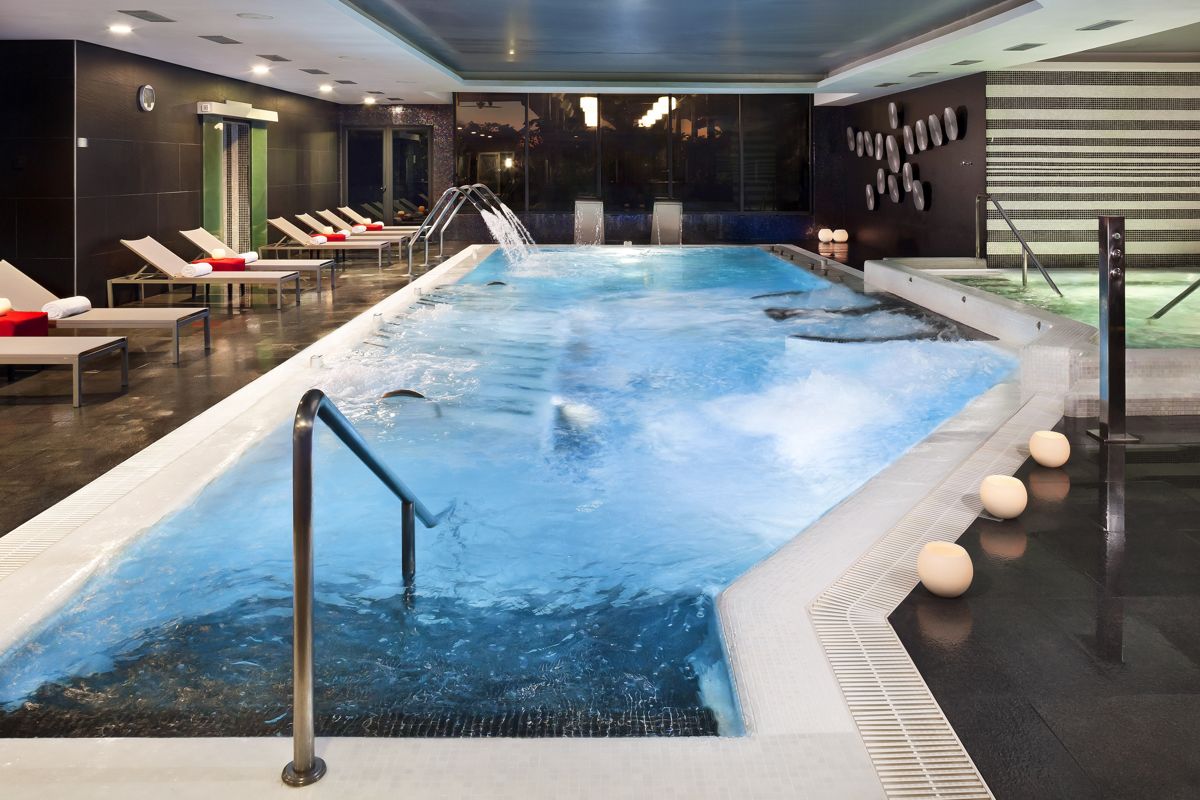 Piscina interior con tumbonas y jacuzzi en un spa en Tenerife.
