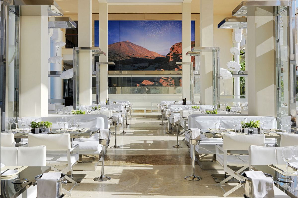 Restaurante elegante con vista al Teide en Tenerife, mesas dispuestas simétricamente.