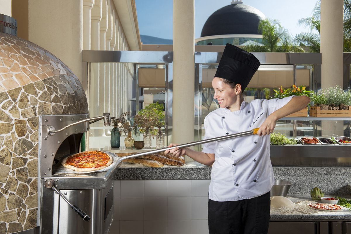 Chef preparando pizza en horno de piedra en restaurante de Tenerife.