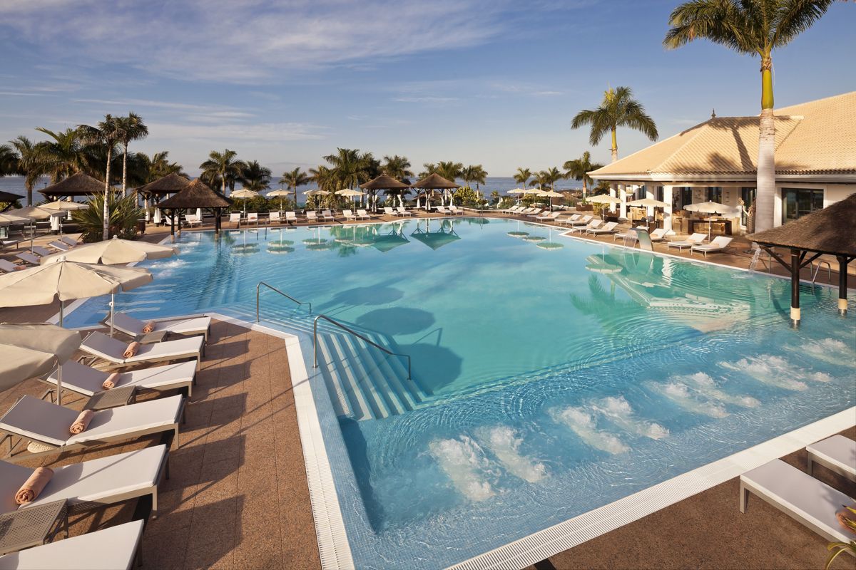 Piscina con tumbonas y sombrillas en un resort en Tenerife.