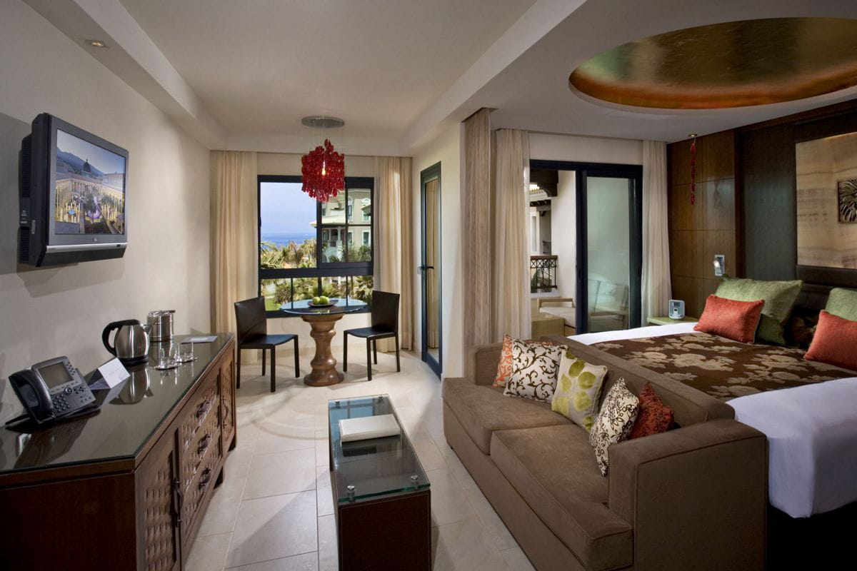Habitación de hotel en Tenerife con cama, sofá y mesa junto a la ventana.