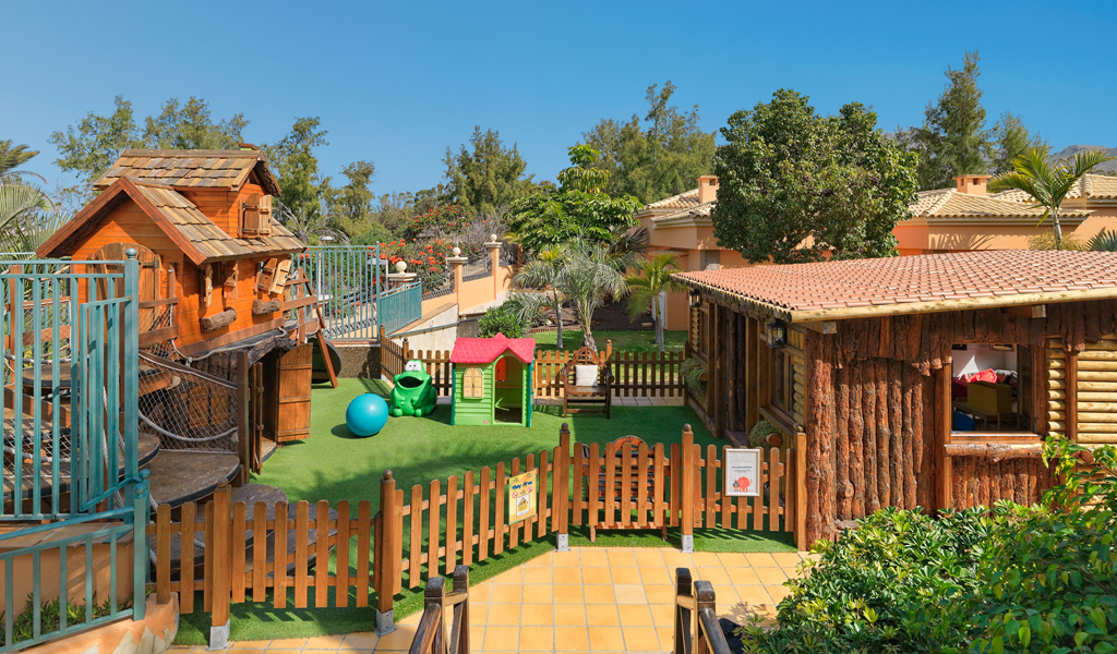 Área de juegos infantiles con cabañas de madera en un parque de Tenerife.